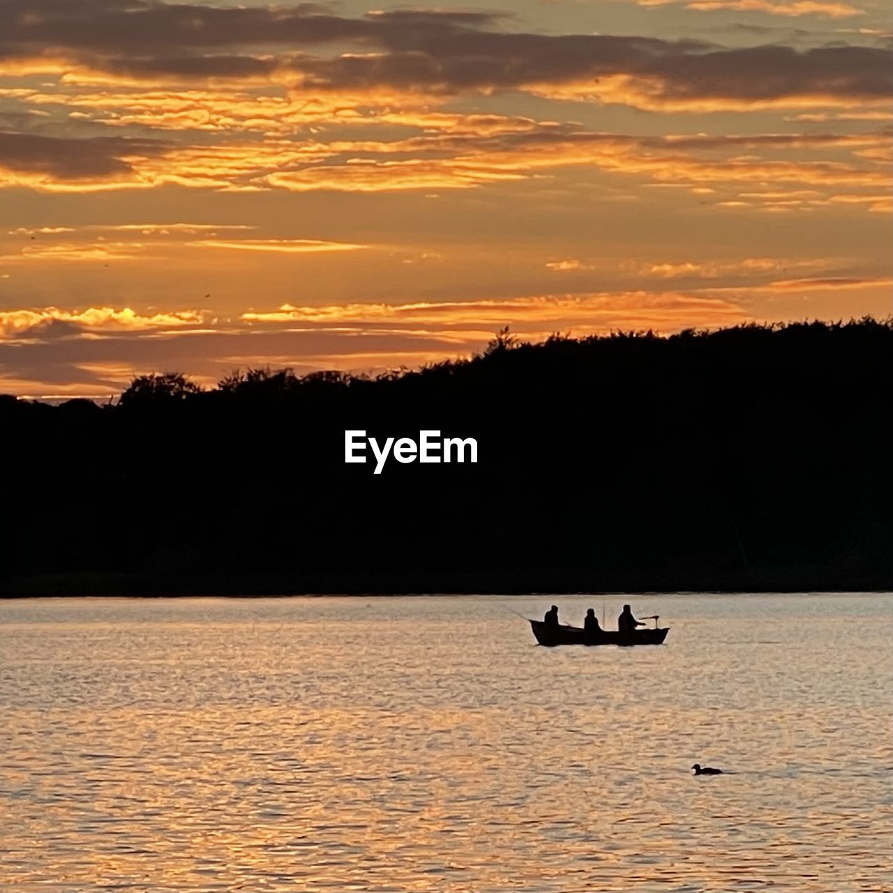 Silhouette people on lake during sunset