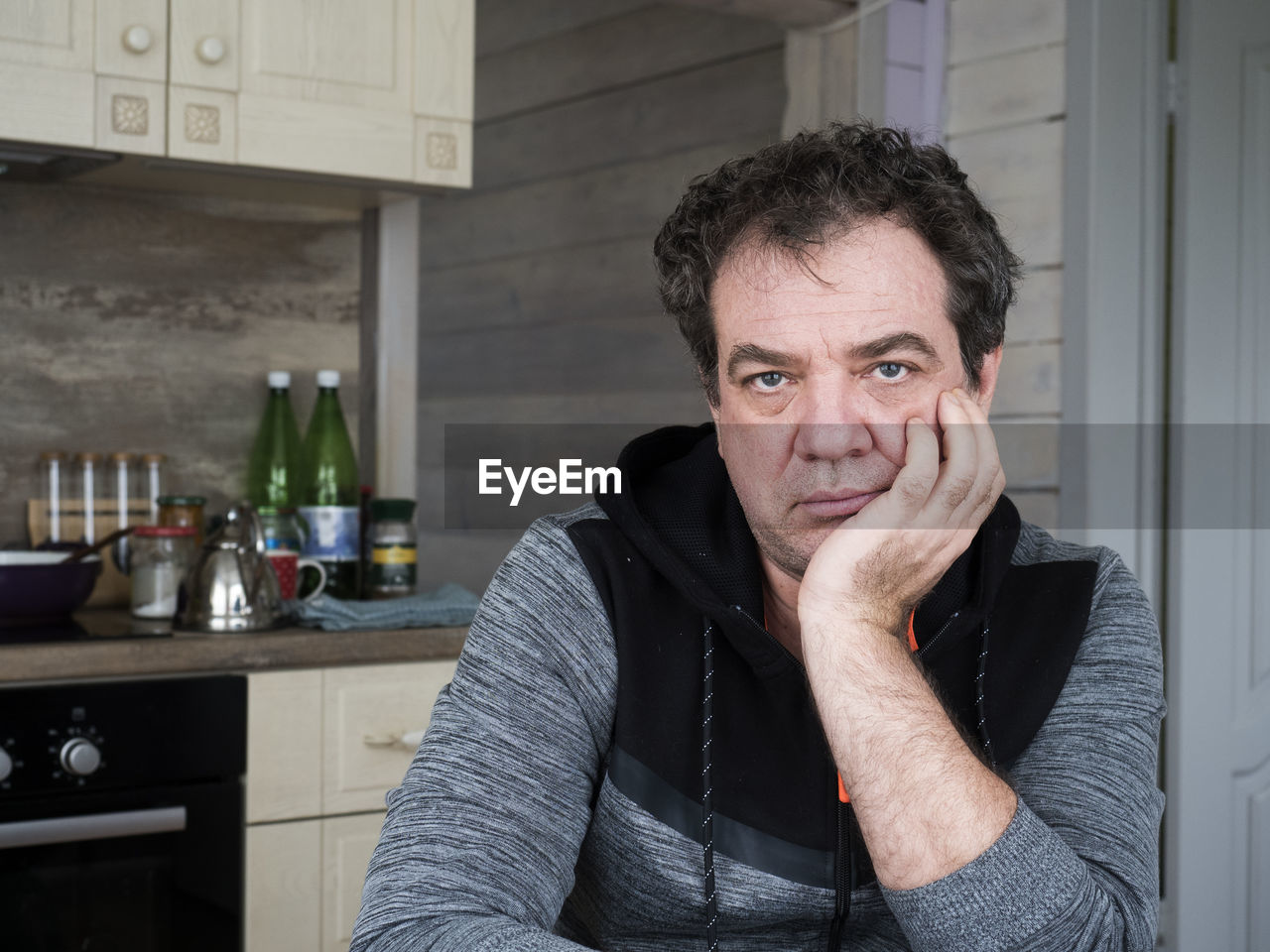 Portrait of mature man sitting in kitchen at home