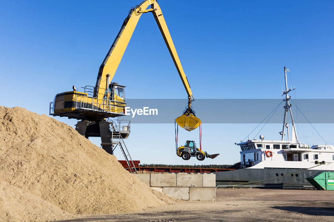 Large crane lifting bulldozer in harbour