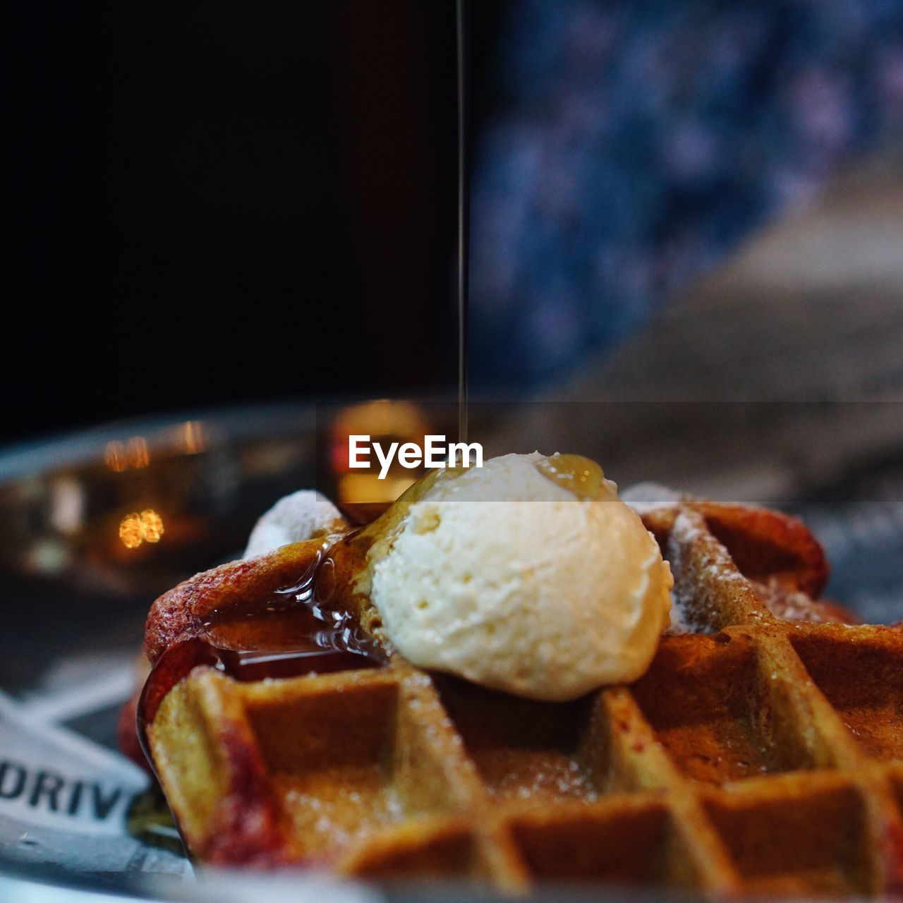 Close-up of syrup being poured on waffle