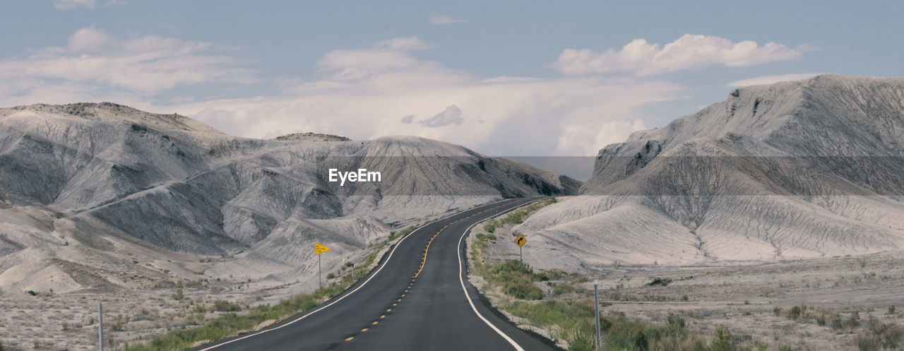 Empty road amidst mountains against sky