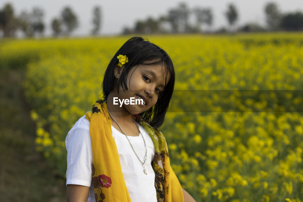 PORTRAIT OF A SMILING YOUNG WOMAN ON FIELD