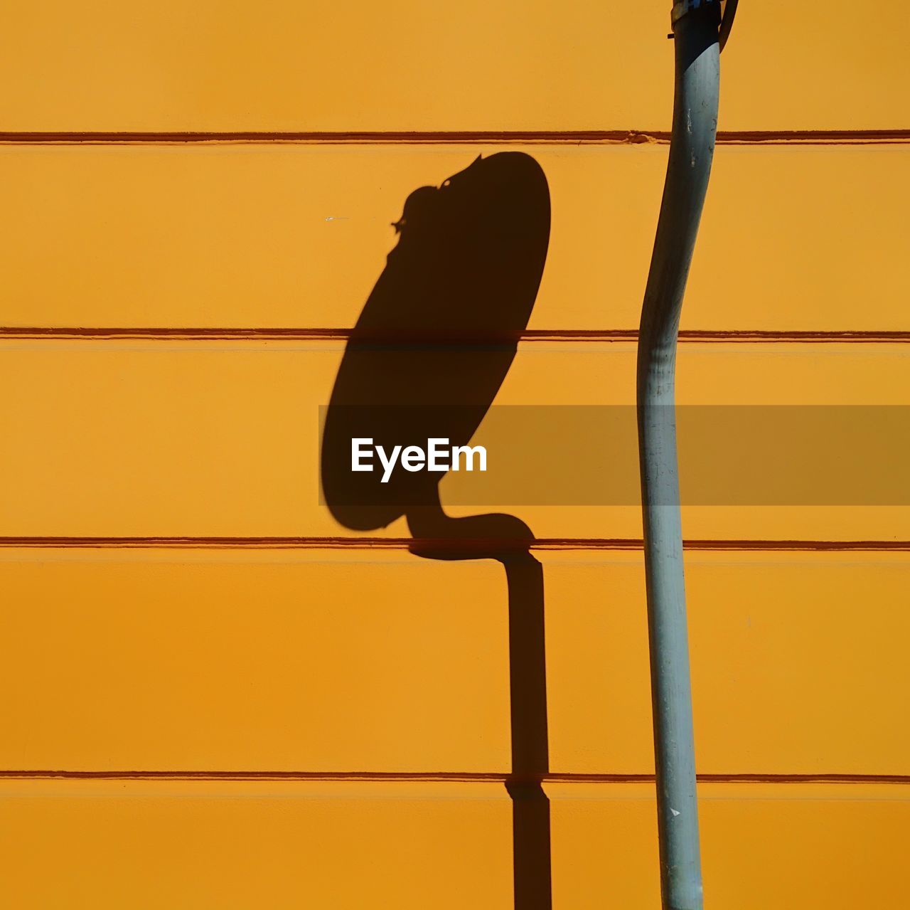 Close-up of shadow of satellite dish on orange wall