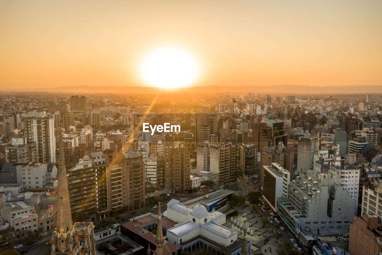 Aerial view of city buildings against sky during sunset