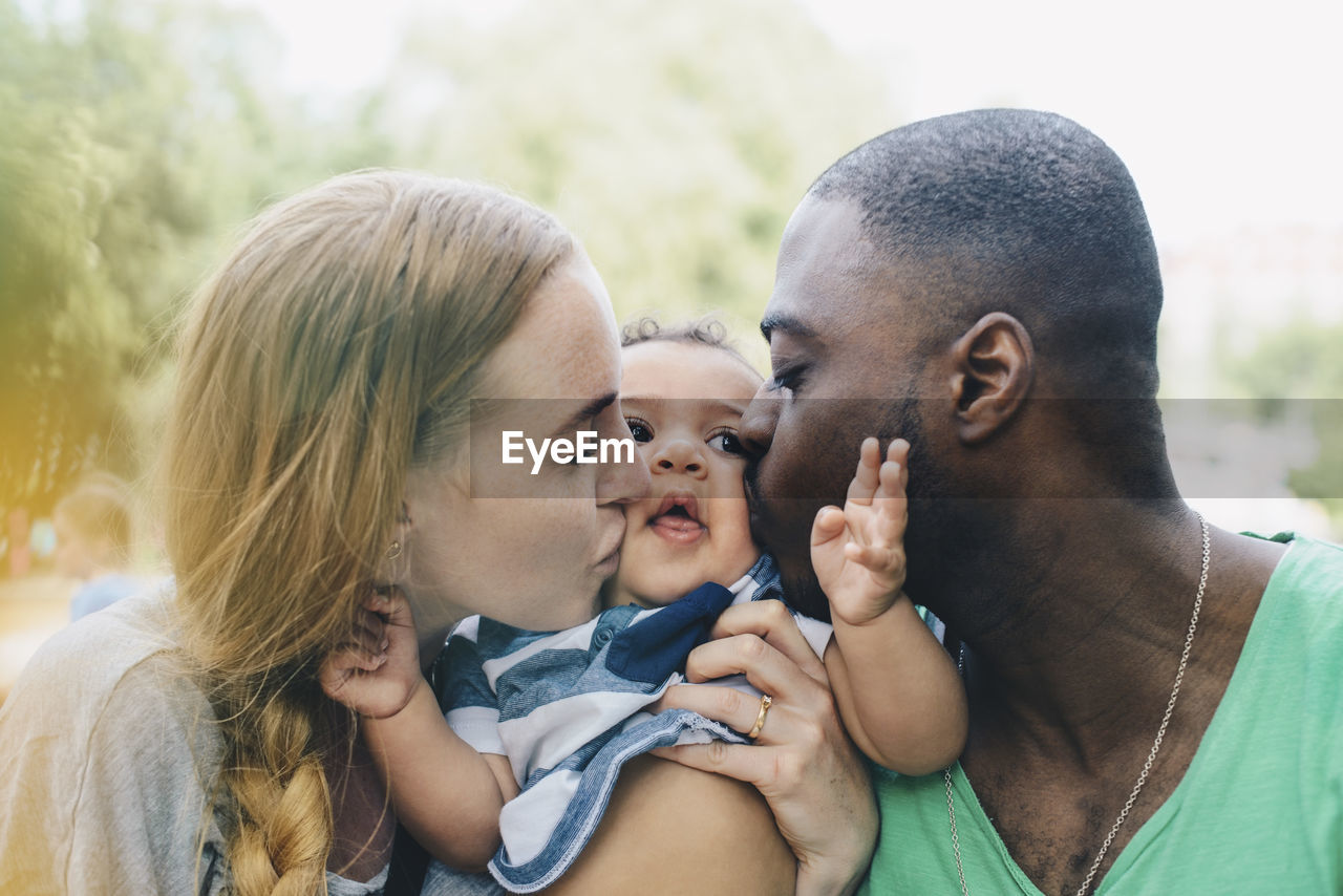 Close-up of multi-ethnic parents kissing son