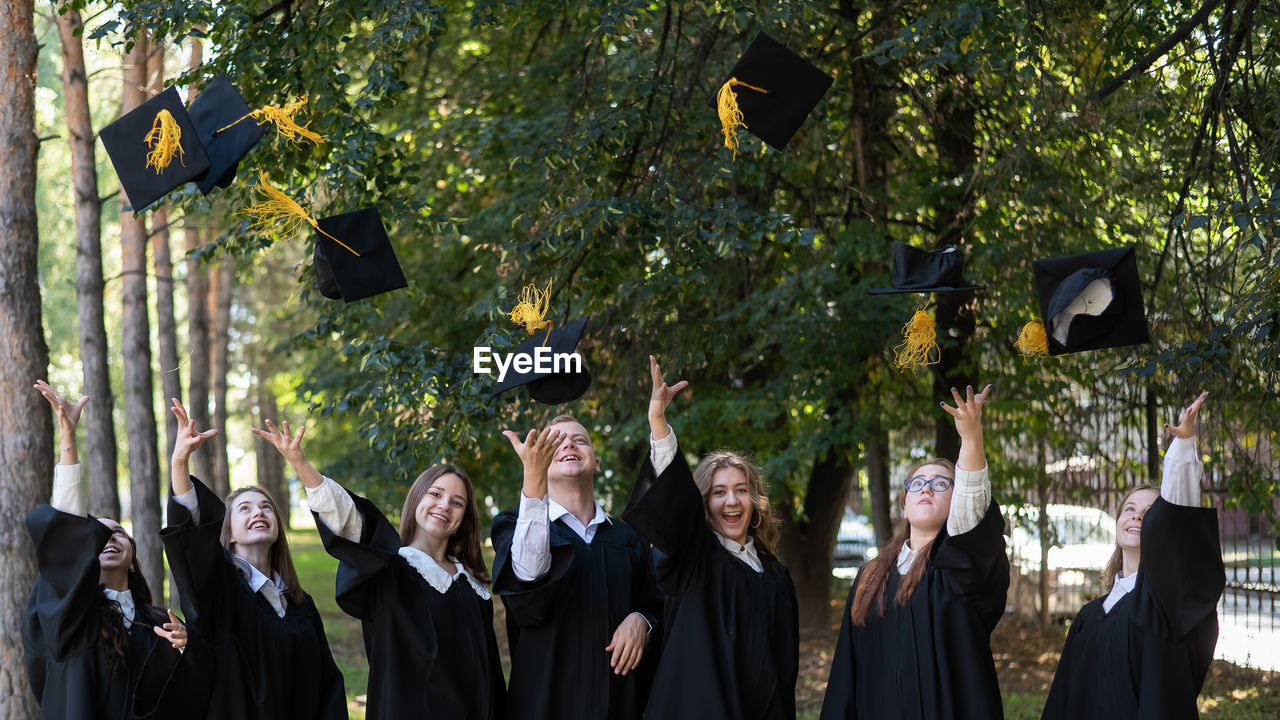 portrait of students wearing graduation gown standing in city