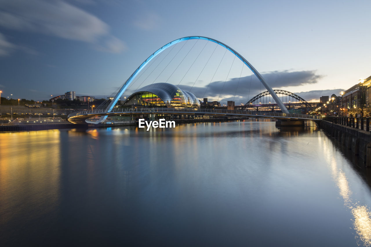 Bridge over river against sky in city