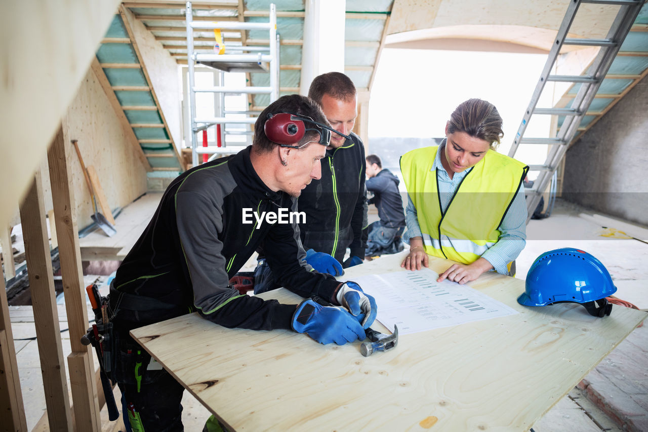 High angle view of construction workers discussing over blue prints at site