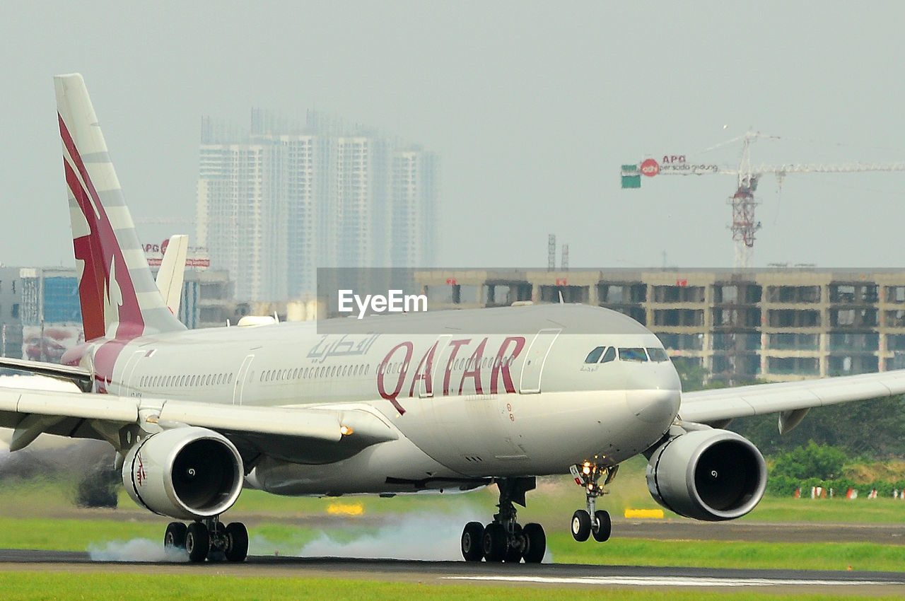 AIRPLANE AT AIRPORT RUNWAY AGAINST SKY