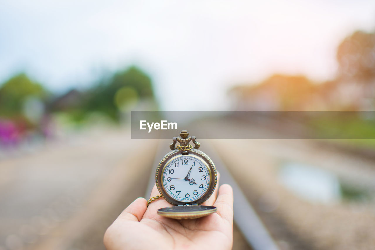 Cropped hand holding pocket watch