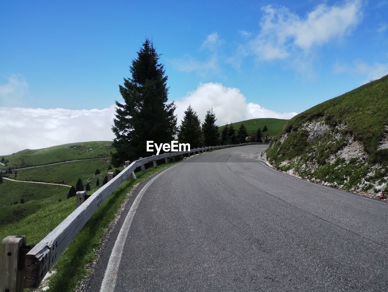 road, sky, transportation, highway, cloud, mountain pass, mountain, nature, landscape, tree, plant, environment, scenics - nature, mountain range, infrastructure, land, no people, travel, non-urban scene, lane, beauty in nature, the way forward, freeway, blue, travel destinations, day, winding road, asphalt, curve, tranquility, tranquil scene, outdoors, road trip, forest, country road, road surface, street, mode of transportation, pinaceae, coniferous tree, journey, empty road, remote, symbol, tourism, mountain road, pine tree, rural scene, sign, motor vehicle