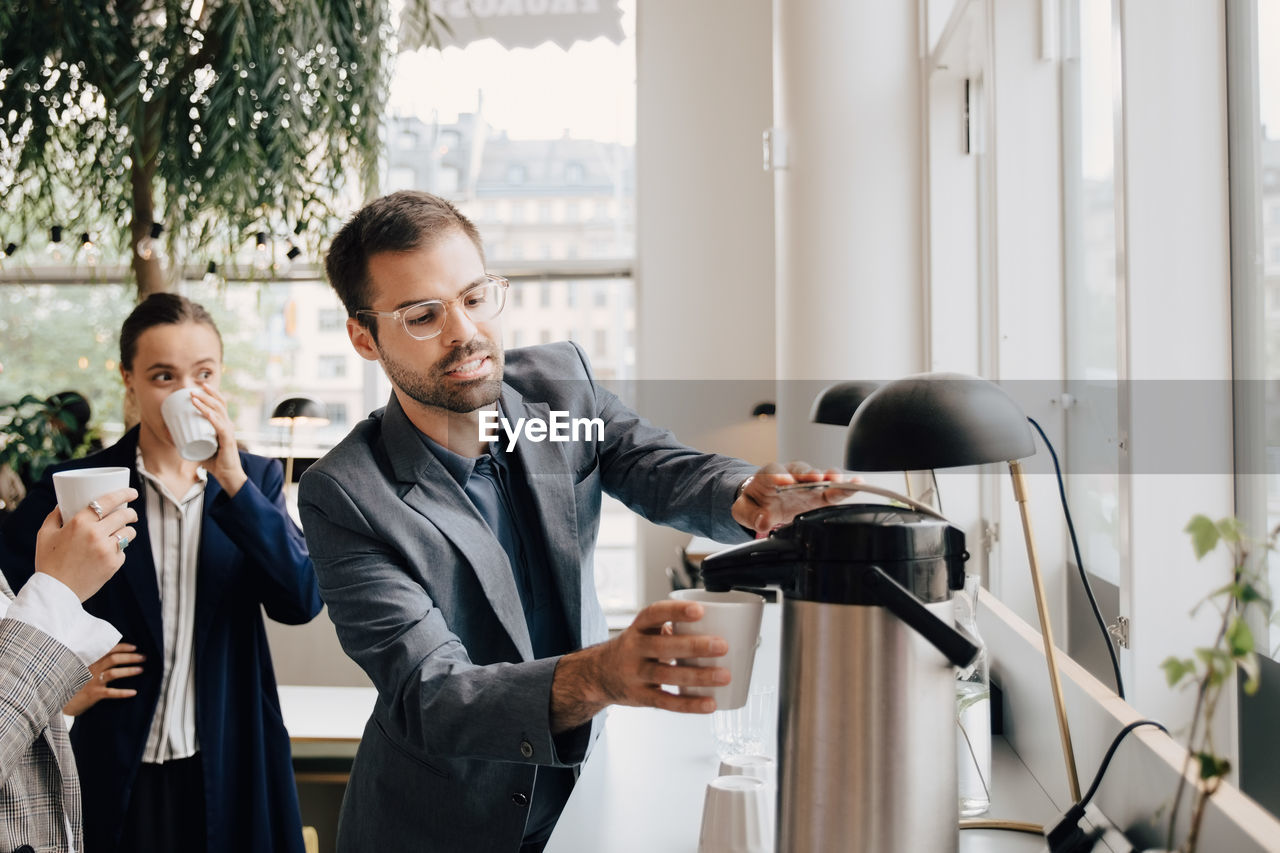 Businessman having coffee with female colleagues at creative office during break