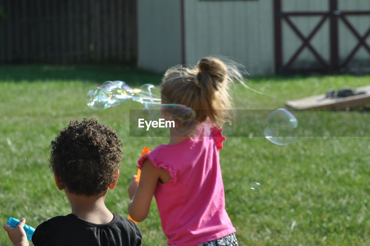 REAR VIEW OF CHILDREN PLAYING IN PARK