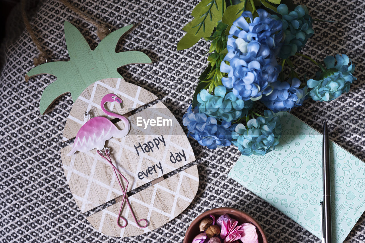 High angle view of card with text by flowers and book on table