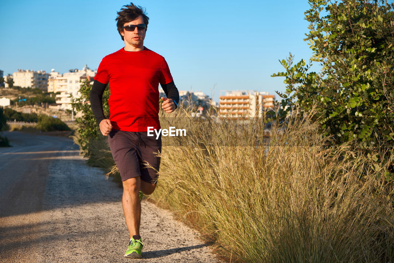 Young man wearing sunglasses on a morning jog in the countryside.