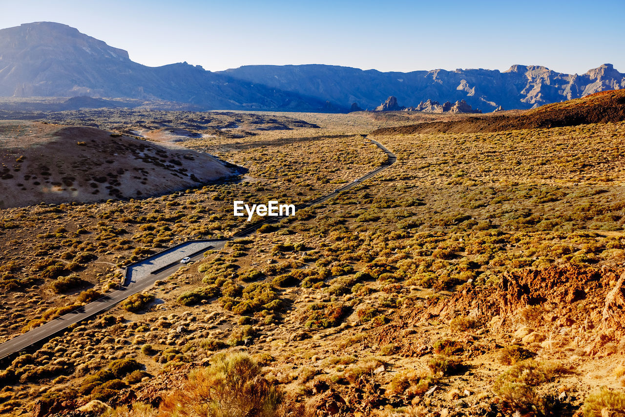 A mountain road crosses a spectacular valley at noon near mount teide.