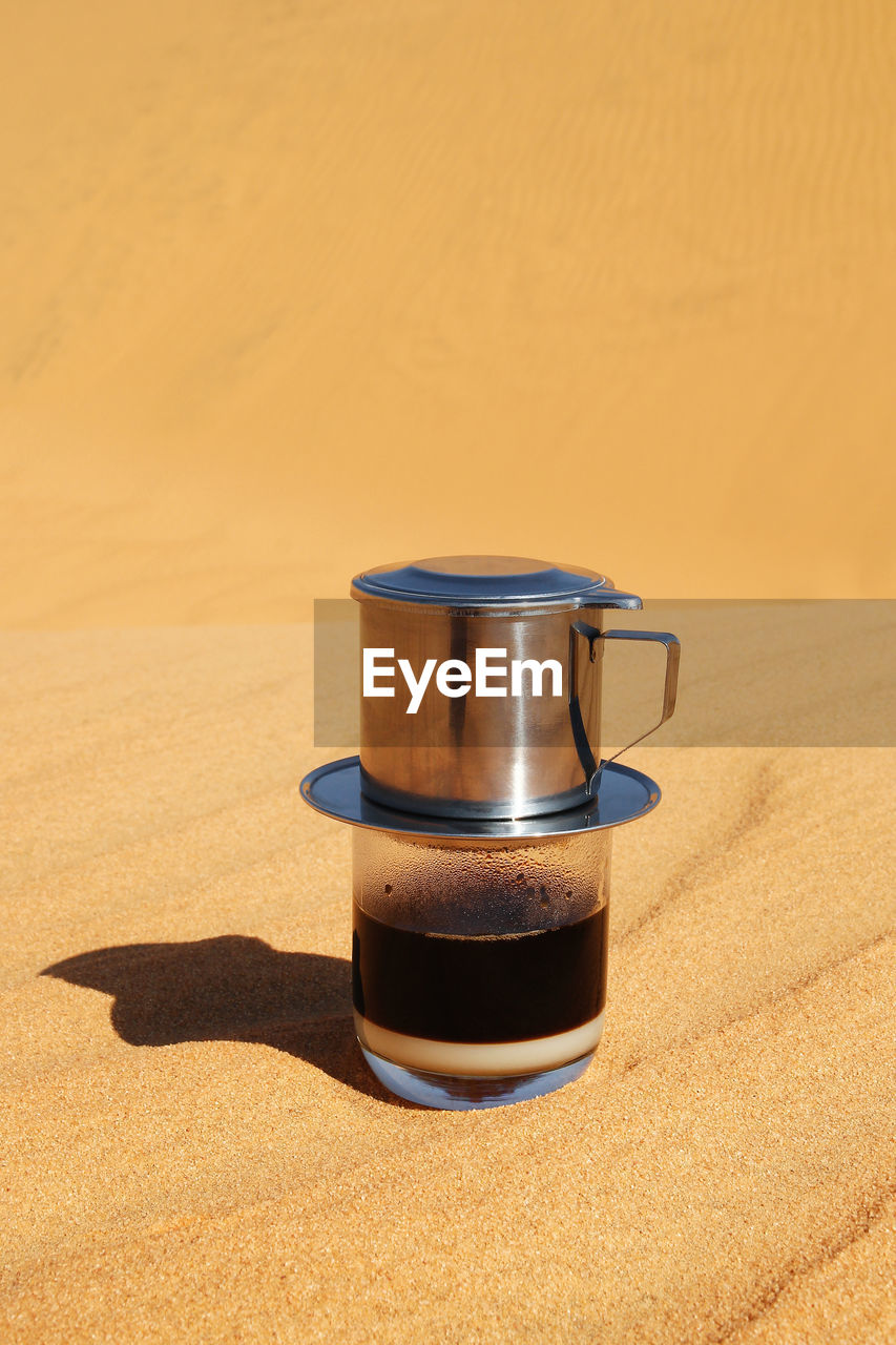 Drip black coffee in vietnamese style with condensed milk on a sand, top method of making coffee.