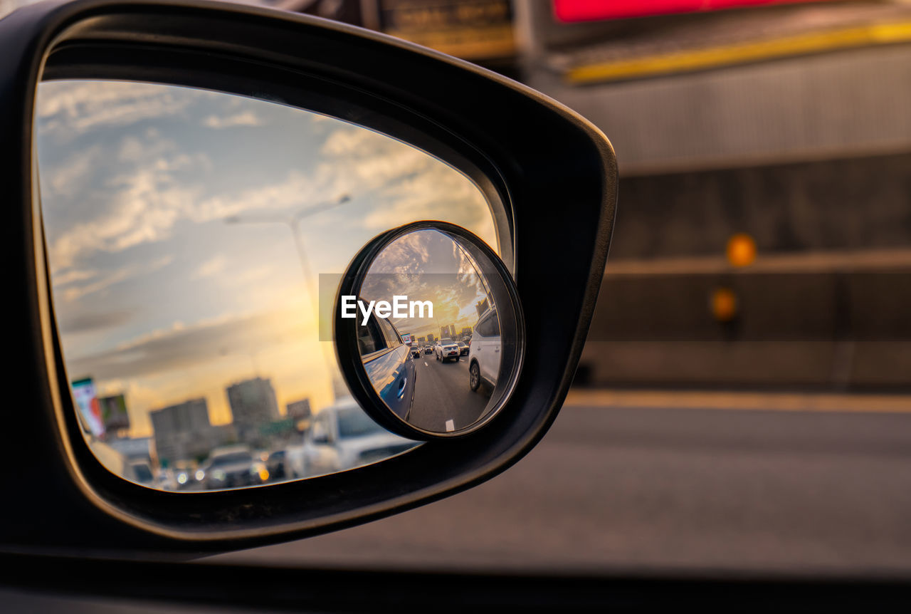 Reflection of traffic flow on asphalt road in side mirror of blue suv. car wing mirror.