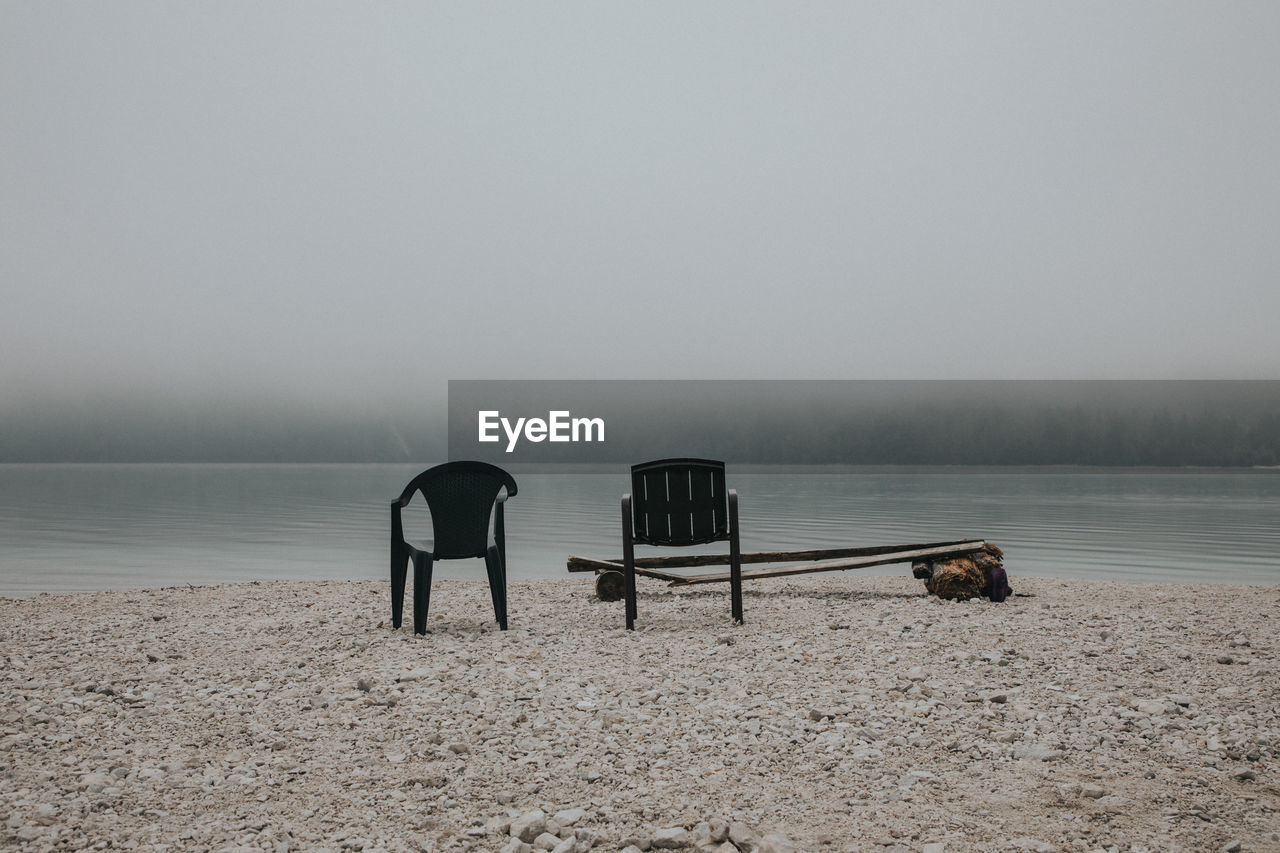 Empty seats in lake against sky