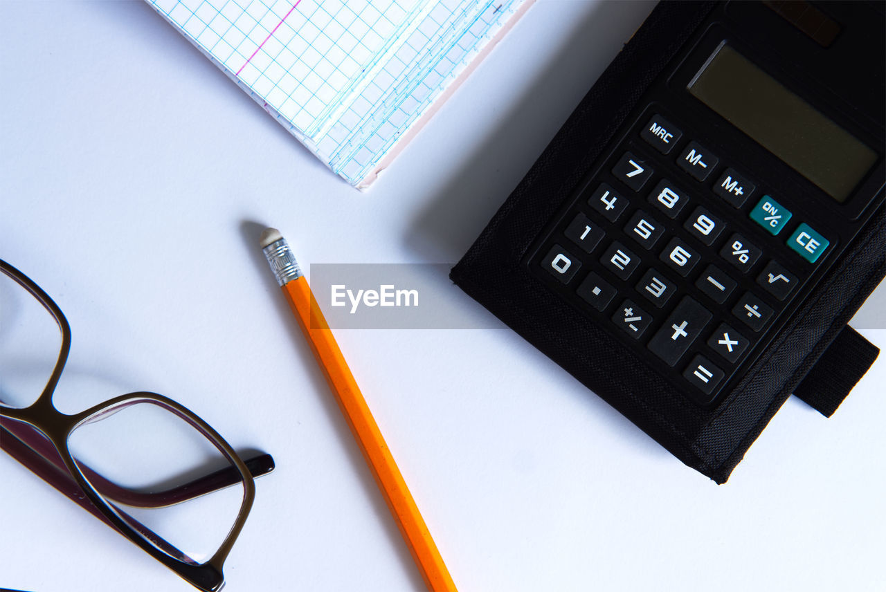 office supplies, technology, business, indoors, eyeglasses, calculator, glasses, no people, high angle view, finance, table, office, studio shot, pencil, desk, communication, pen, number, paper, still life, font, education, wireless technology, close-up, computer