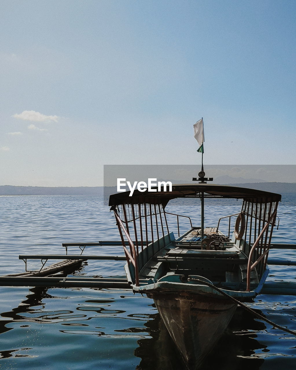 Fishing boat moored on sea against sky