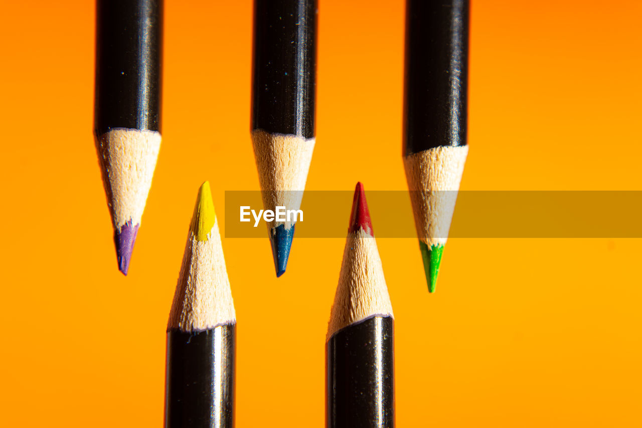 Close-up of colored pencils against yellow background