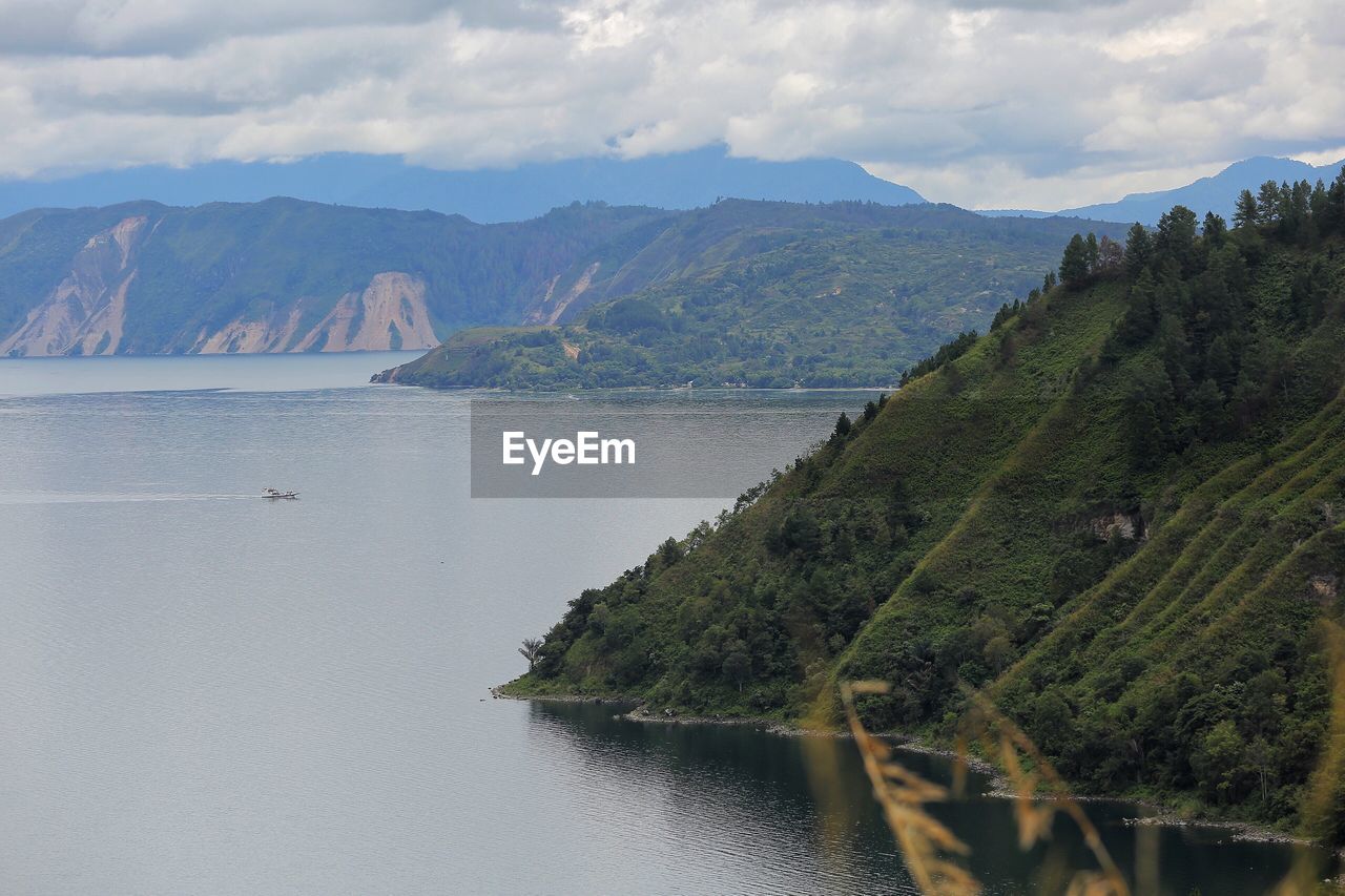 Scenic view of river by mountains against sky