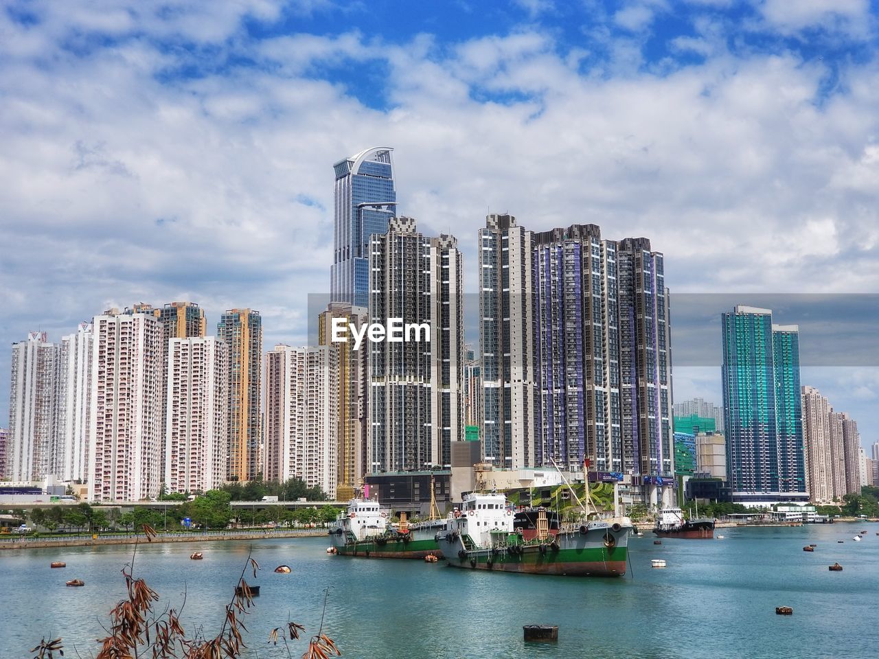 Modern buildings by lake against cloudy sky