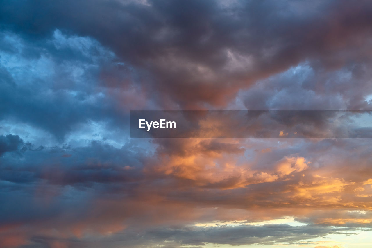 LOW ANGLE VIEW OF STORM CLOUDS AT SUNSET