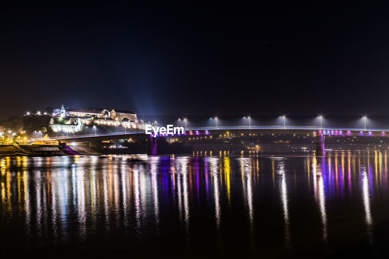 View of illuminated bridge over river at night
