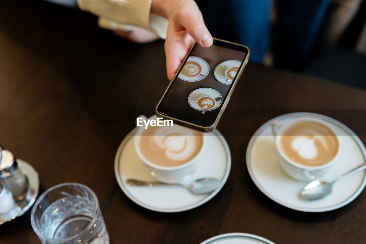 Photographer taking pictures of coffee on mobile phone