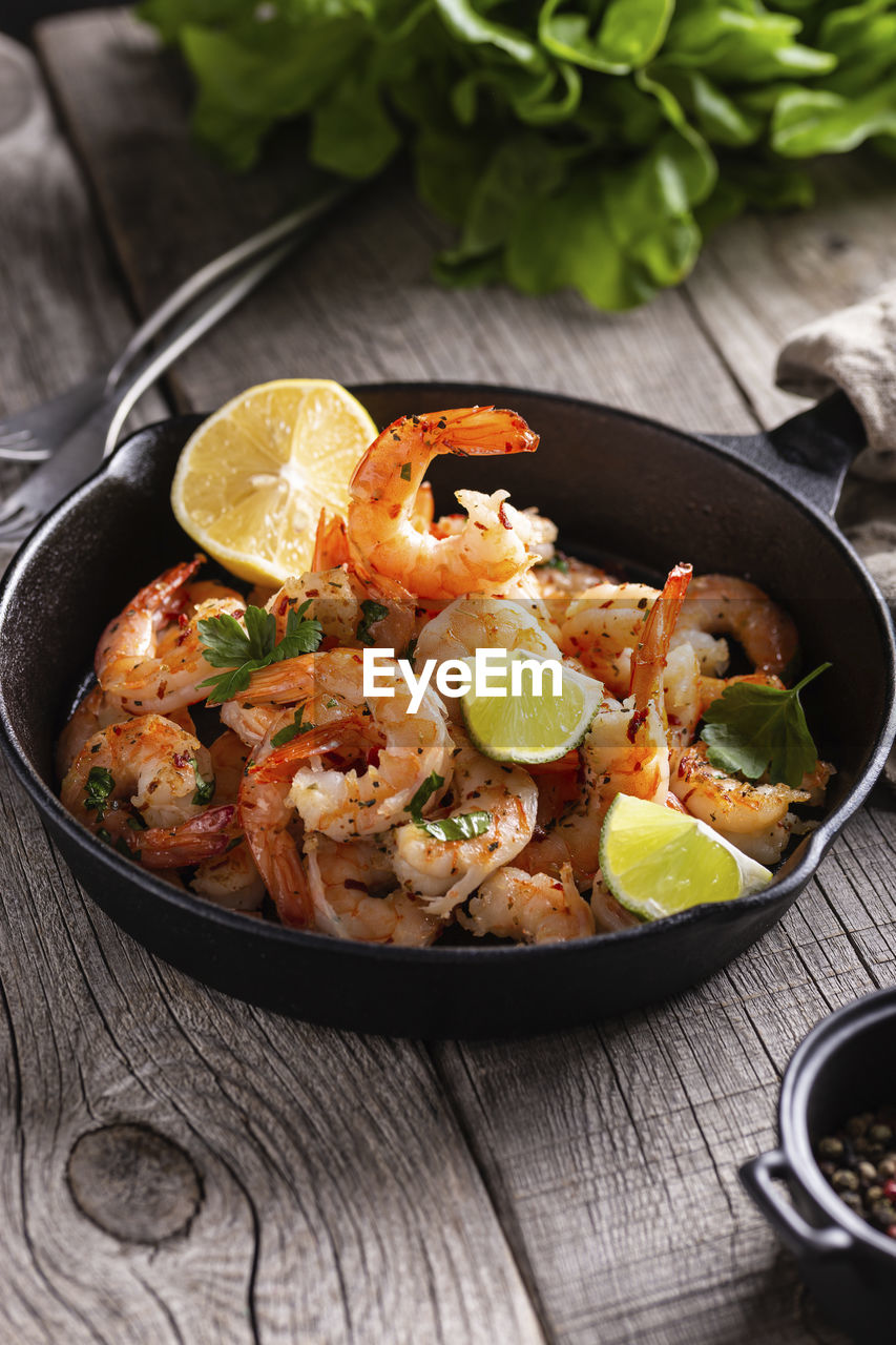 food and drink, food, healthy eating, dish, fruit, wood, freshness, vegetable, citrus fruit, wellbeing, herb, studio shot, lemon, no people, spice, kitchen utensil, cuisine, produce, meal, indoors, rustic, seafood, crockery, high angle view, savory food, slice, bowl, pan, meat, plant, fish, cooking pan, household equipment, dark