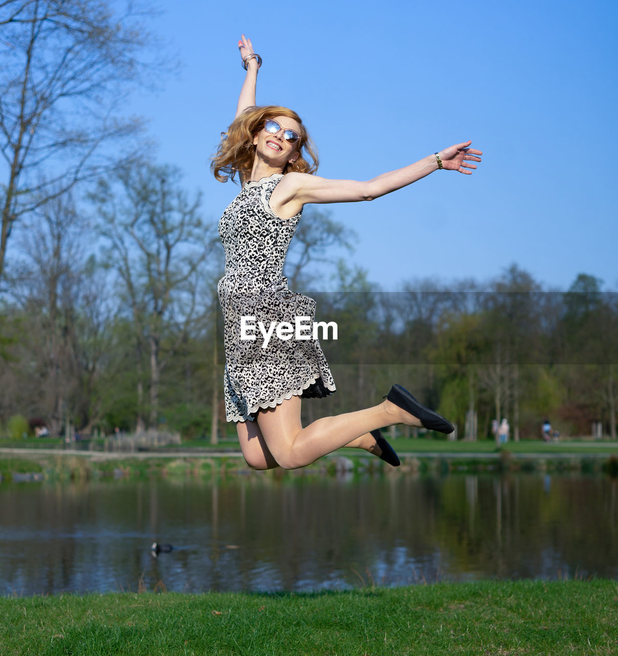 Full length of woman jumping against lake