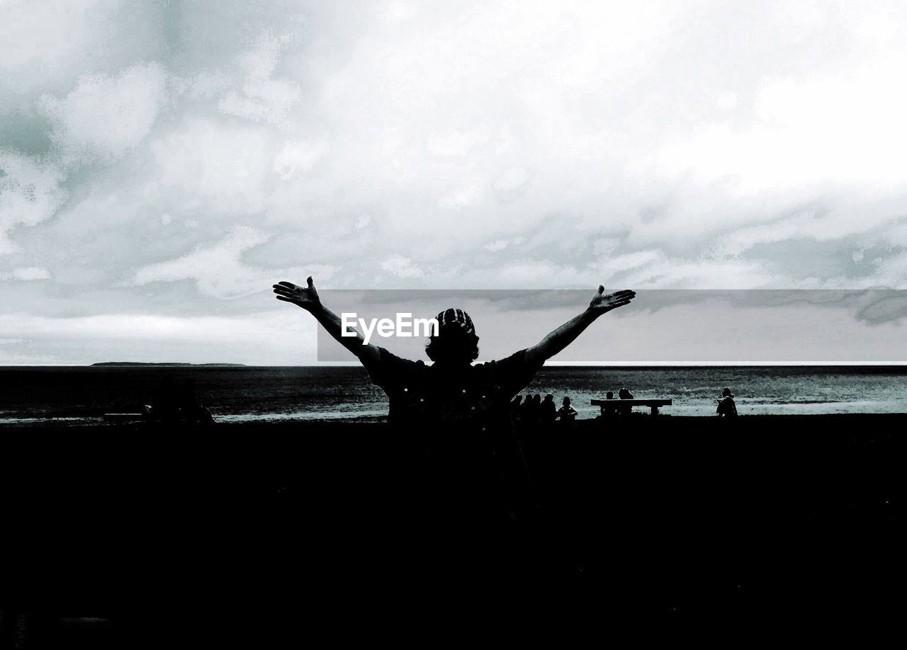 Rear view of man with arms outstretched at beach