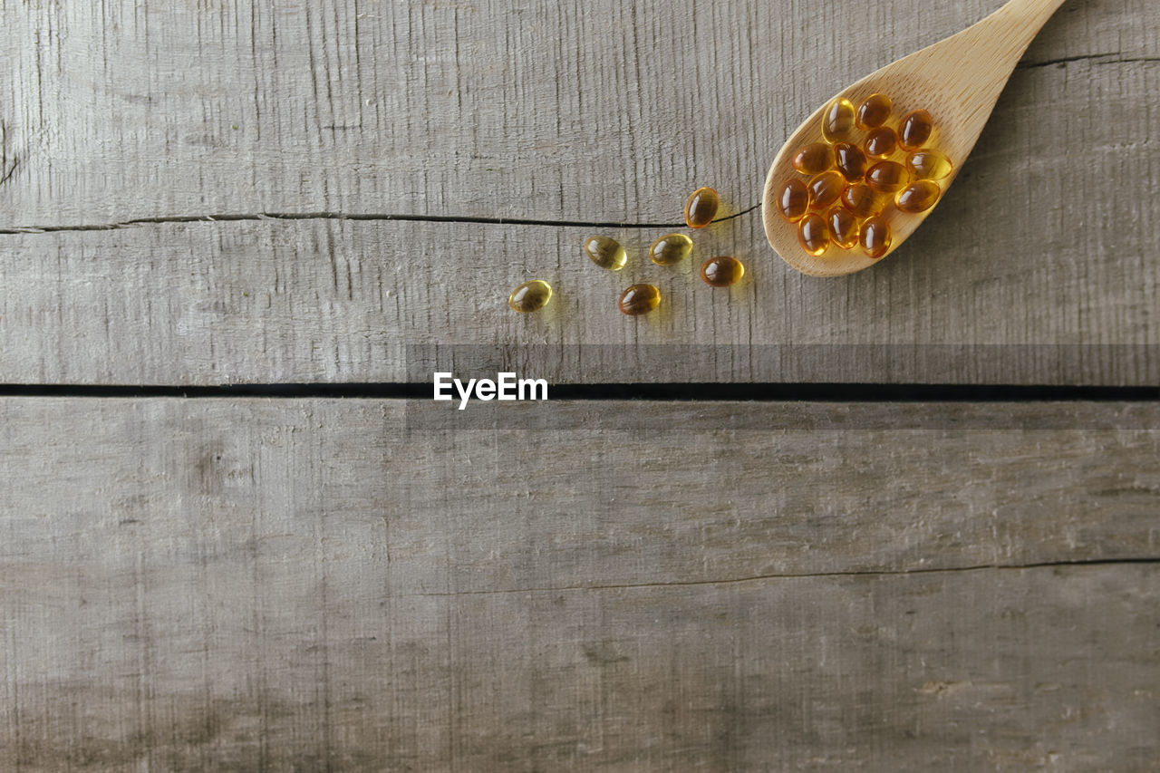 Flat lay with omega 3 capsules on spoon on the wooden background. health concept. vitamin pills