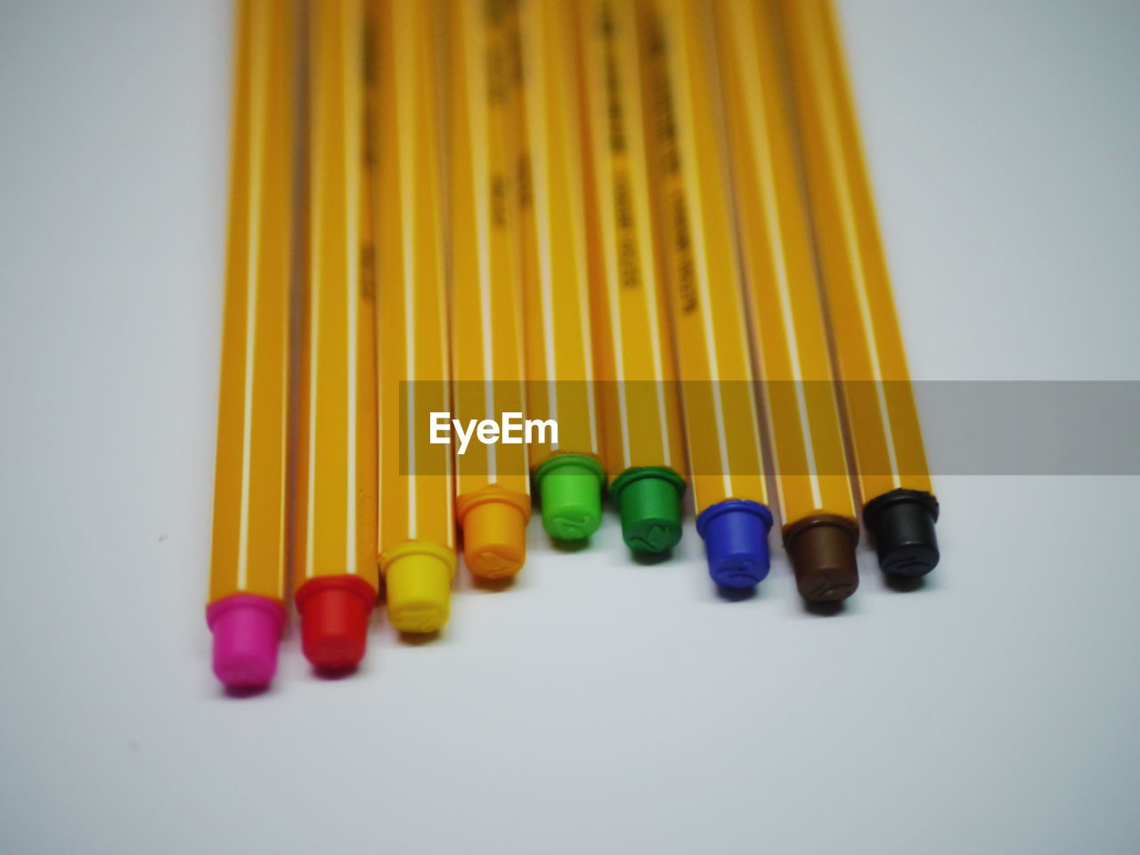 CLOSE-UP OF COLORED PENCILS OVER WHITE BACKGROUND