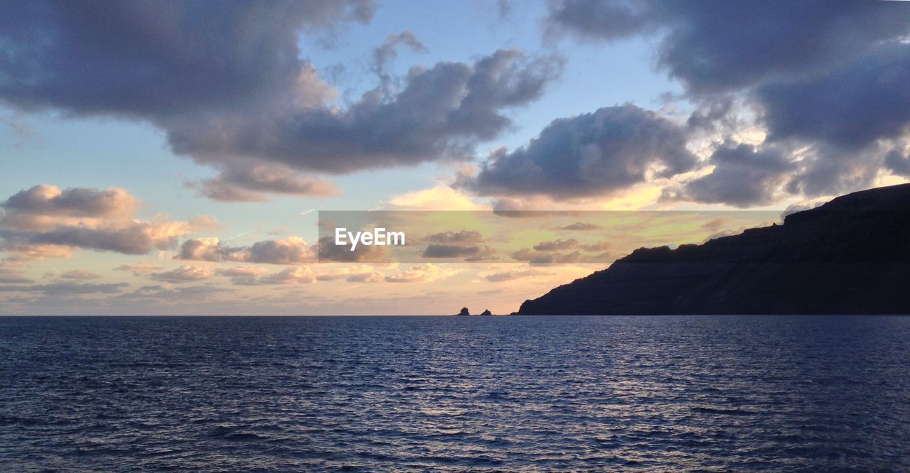 Scenic view of sea against cloudy sky at dusk