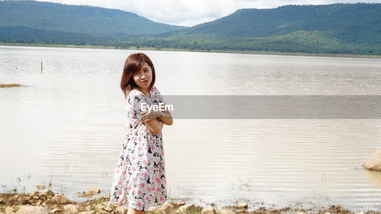 Side view of young woman standing at riverbank