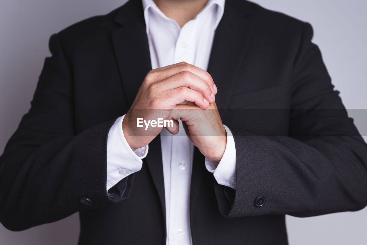 Midsection of businessman wearing black suit while gesturing