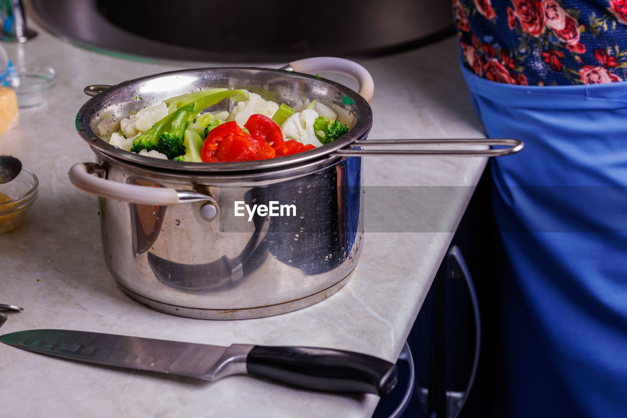 Chopped boiled vegetables in colander in stainless steel cooking pot close-up