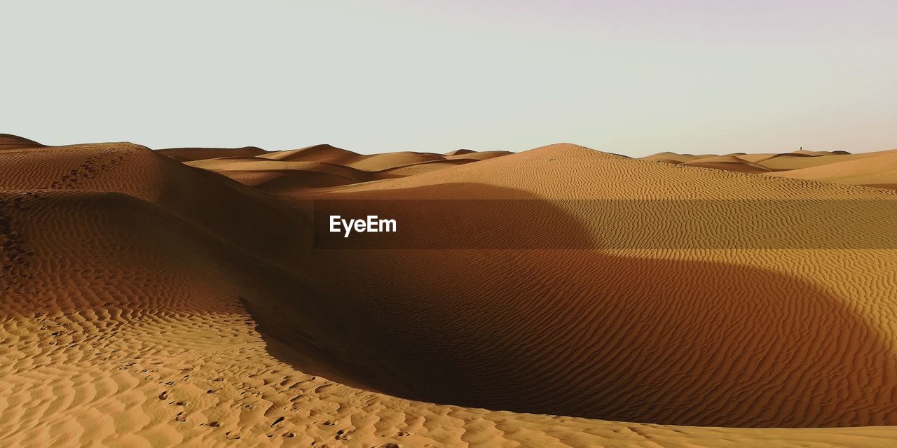 Sand dunes in desert against clear sky