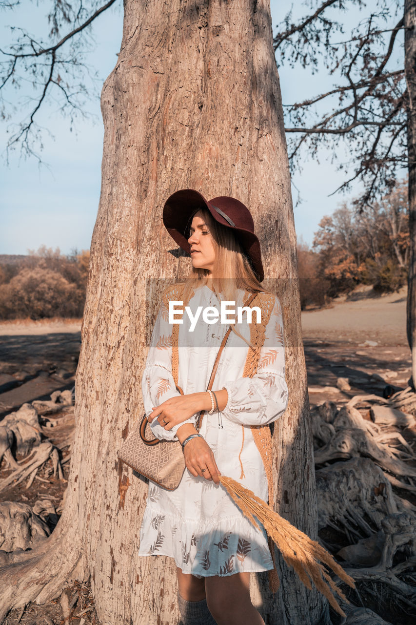 Woman standing by tree trunk