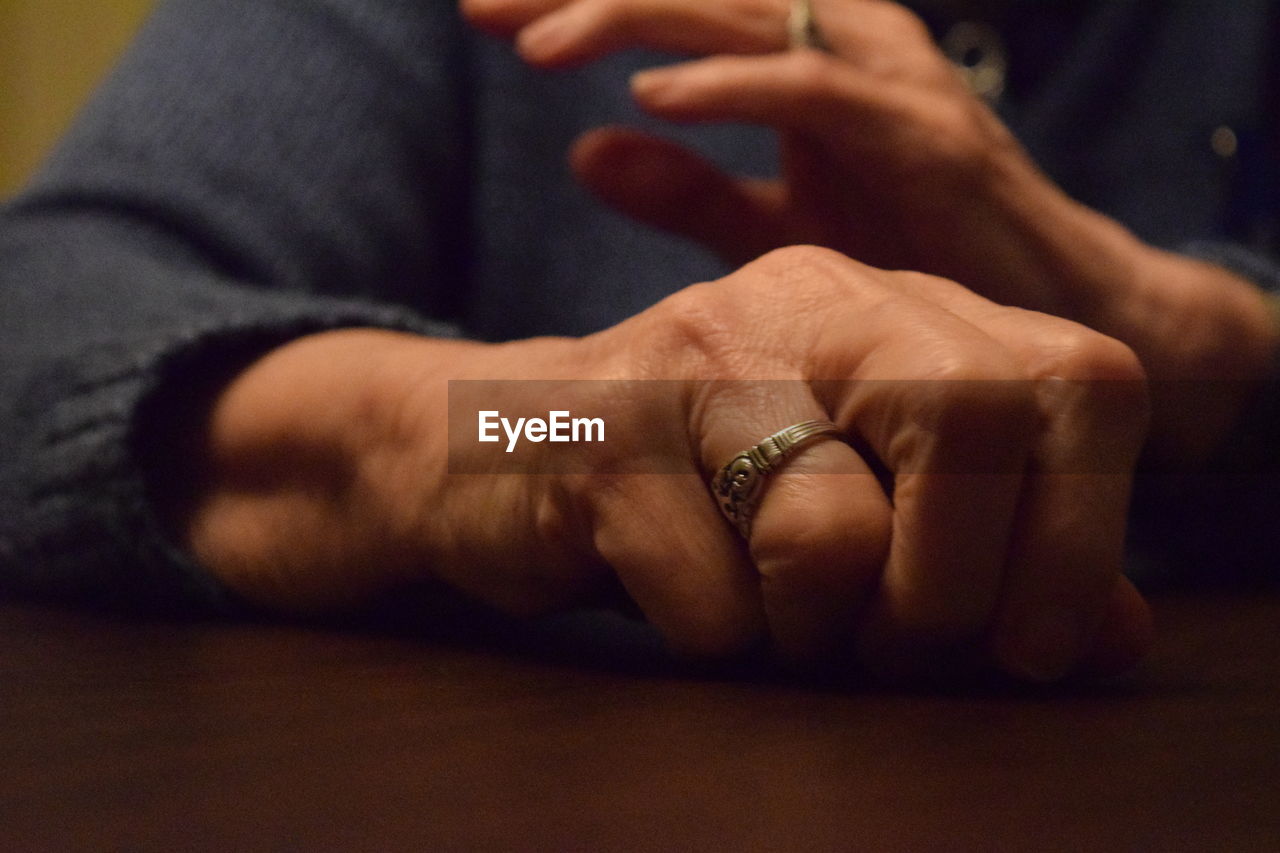 Close-up of person wearing finger ring on table at home