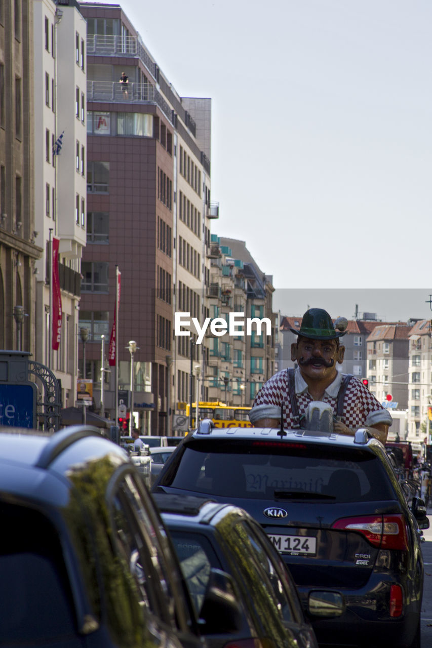 MAN IN CAR AGAINST SKY IN CITY