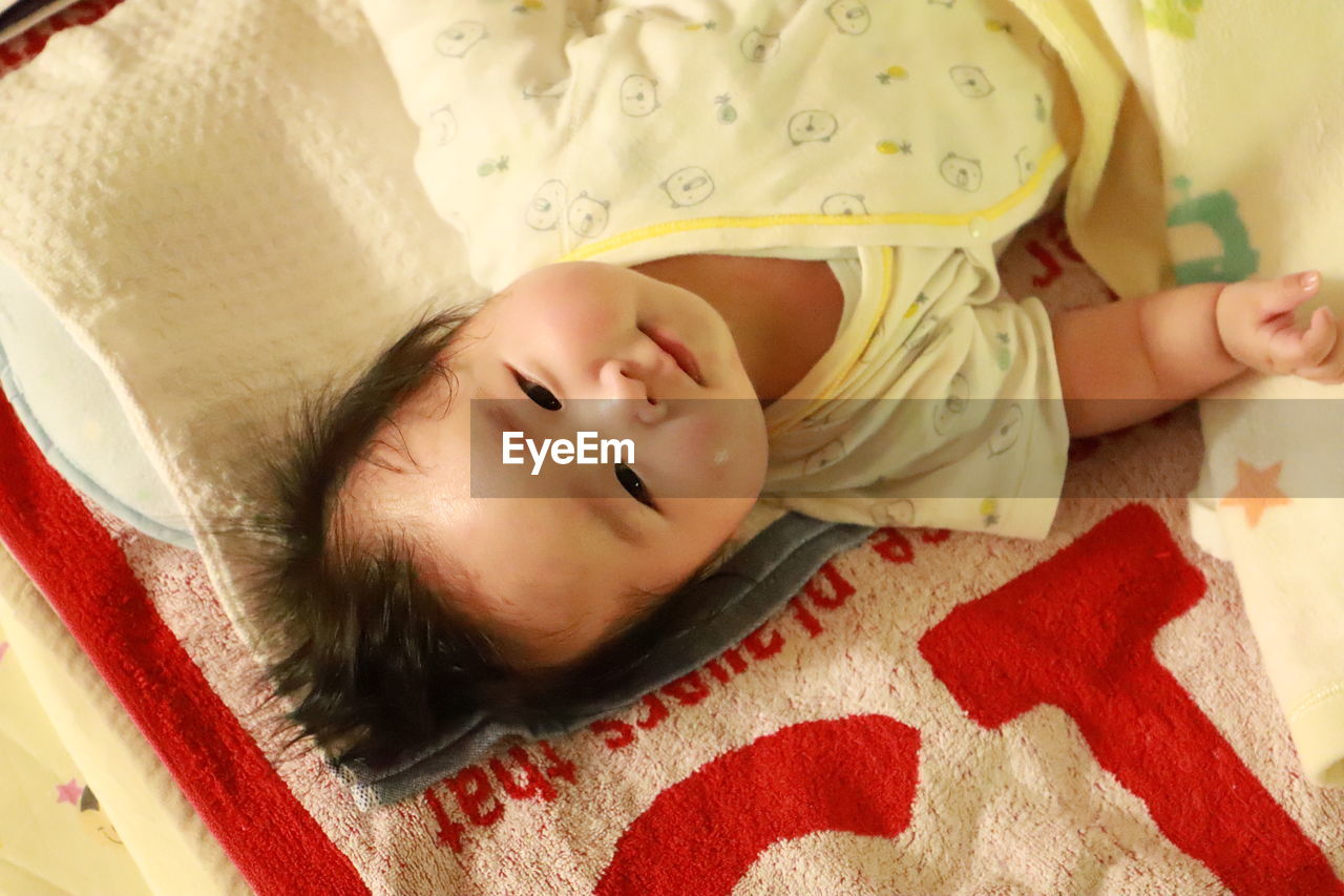 HIGH ANGLE PORTRAIT OF CUTE BOY SLEEPING ON BED