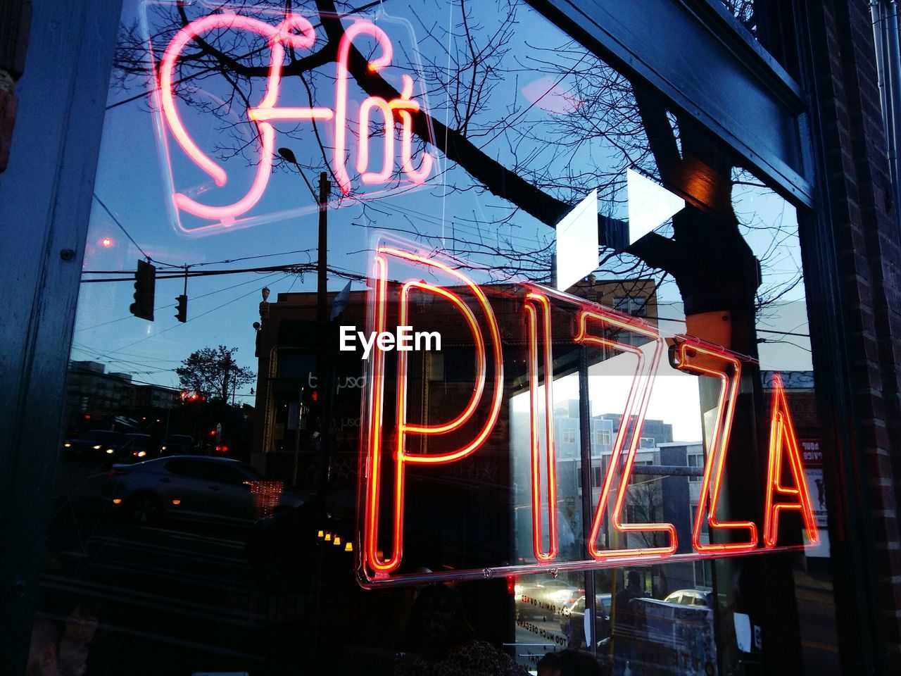 Close-up of neon sign for hot pizza at sunset