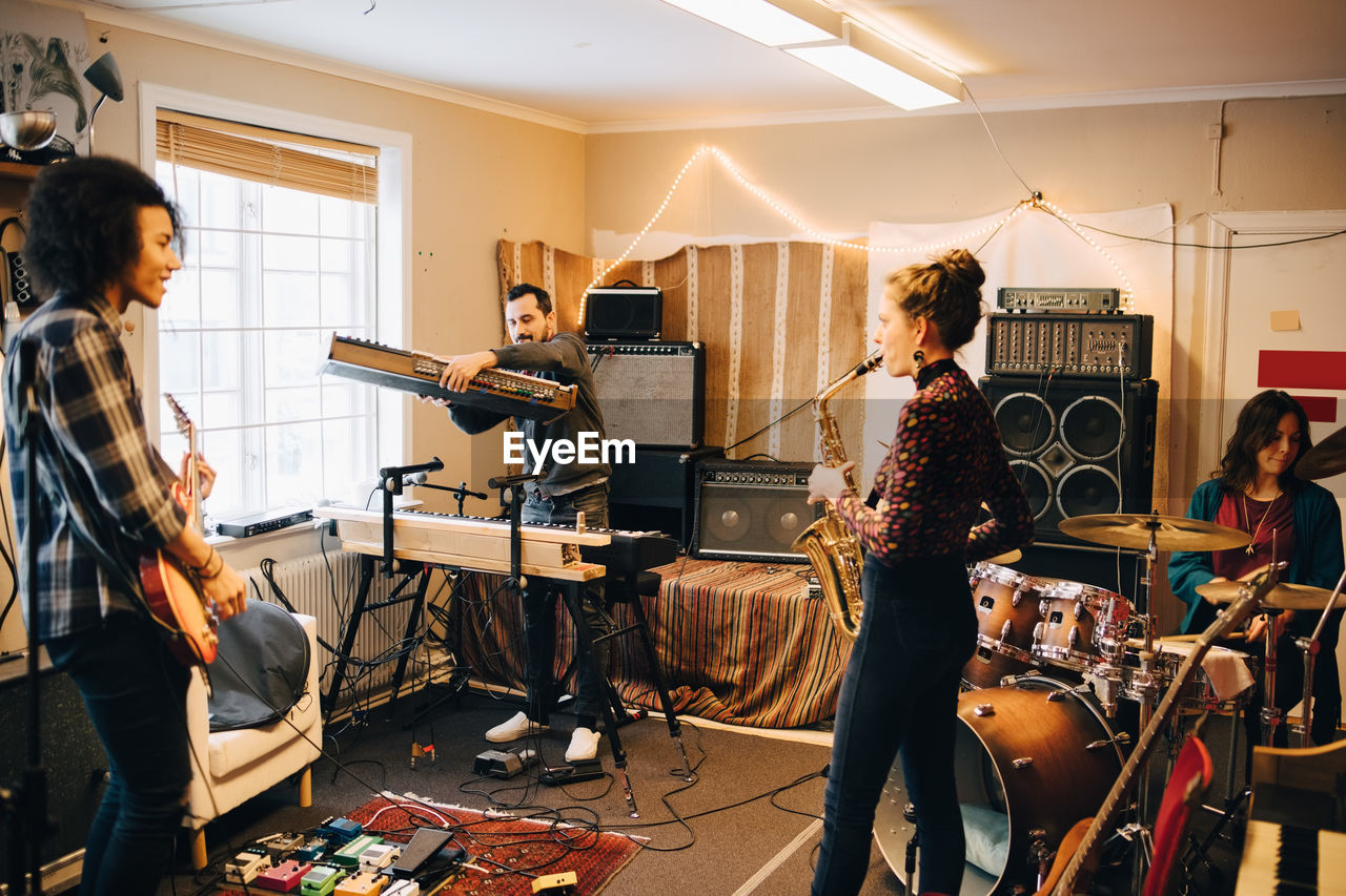 Male and female friends playing various instruments at recording studio