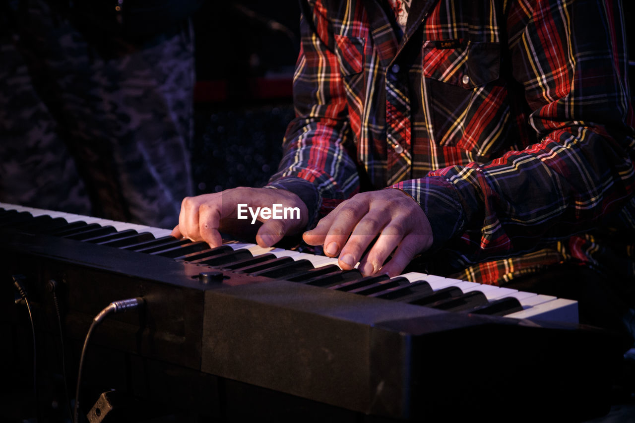 Midsection of man playing keyboard instrument