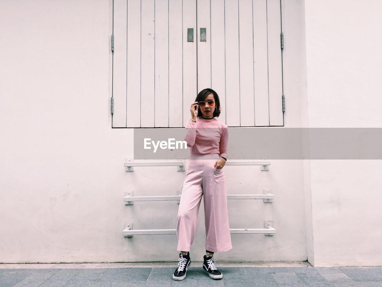 Portrait of young woman standing against wall