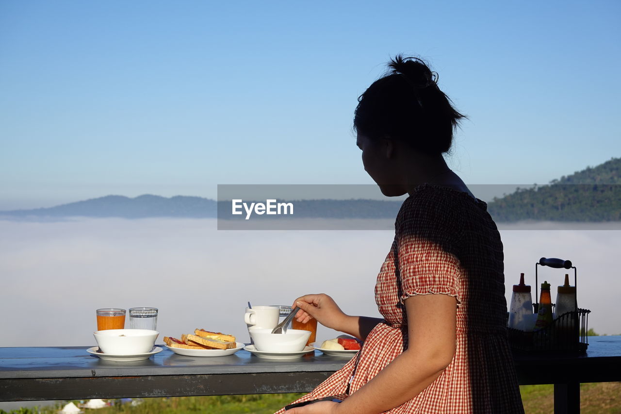 WOMAN SITTING ON COFFEE AGAINST SKY